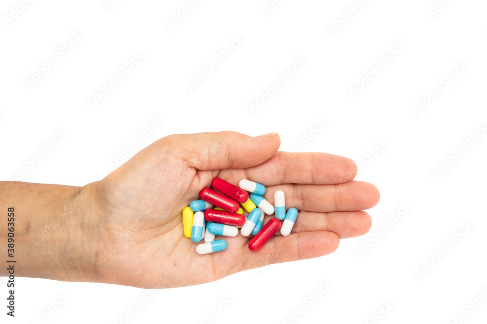 A female hand with multiple colors pills on white background, concept for take your medication