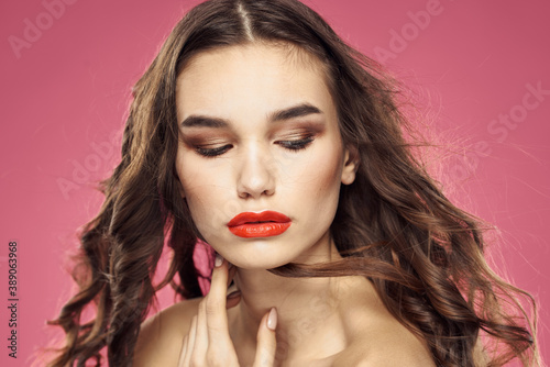 Attractive woman fashionable hairstyle bared shoulders and red lips pink background