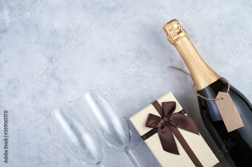 Christmas background with a bottle of champagne, wine glasses and a gift box on a gray background. The concept of New year and Christmas.