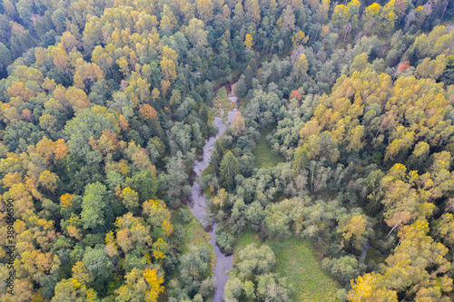 Aerial top down view of winding river flowing through green forest