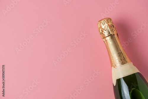 Billede på lærred Champagne bottle on pink background with copy space for text