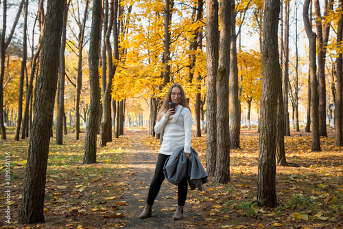 A young beautiful girl walks in the park on a sunny autumn day.