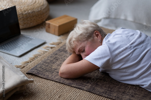 woman relaxes in yoga asana Makarasana or crocodile pose during online lesson photo