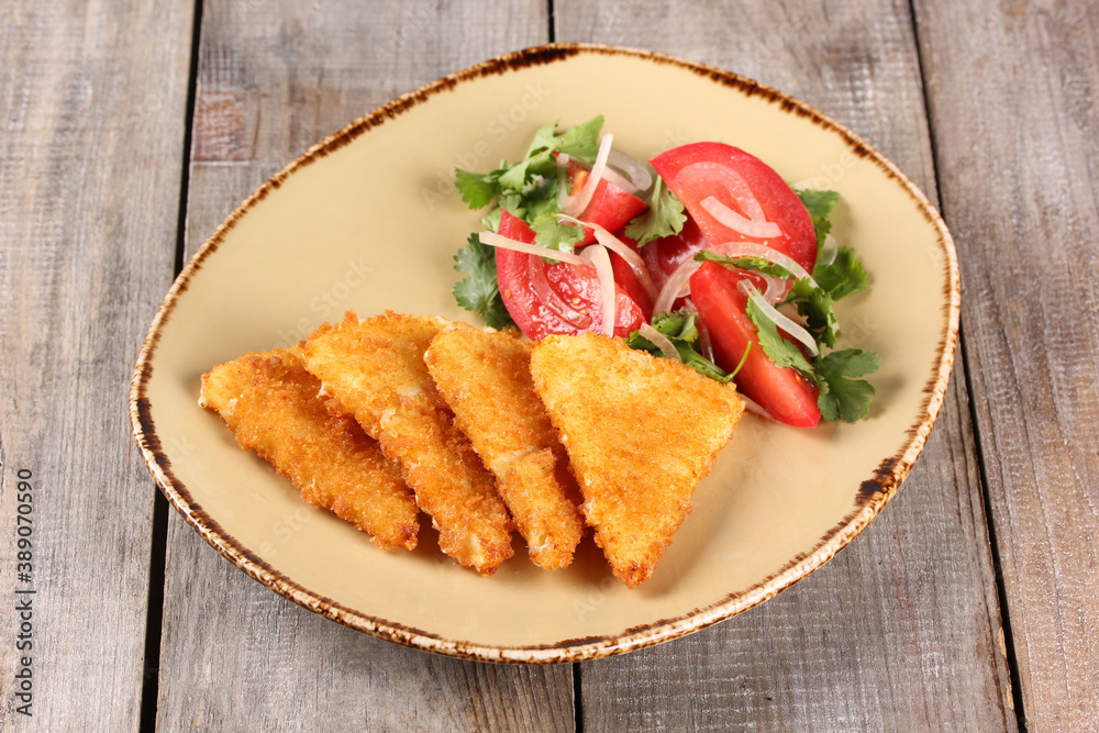 Georgian cuisine. Fried suluguni with tomato, onion and coriander salad in a beige plate on a wooden background. Rustic. Background image. Restaurant menu Georgian cuisine. Fried suluguni with tomato, onion and coriander salad in a beige plate on a wooden background. Rustic. Background image. Restaurant menu
