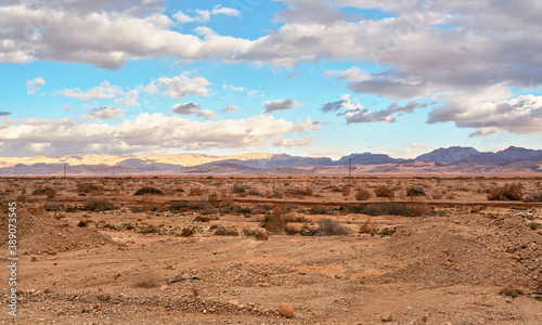 Typical landscape at Israel Jordan border. Flat dry desert with low bushes and small mountains, sun shines through evening clouds