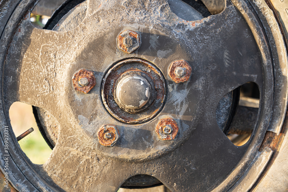 Close-up of a truck wheel of the forties of the 20th century. The green paint is partially peeling, rust is visible on the nuts. Background. Texture. Close-up of a truck wheel of the forties of the 20th century. The green paint is partially peeling, rust is visible on the nuts. Background. Texture.