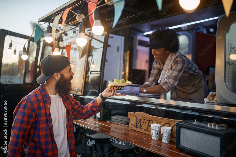 beardy hipster taking sandwich to go from polite female employee in fast food service