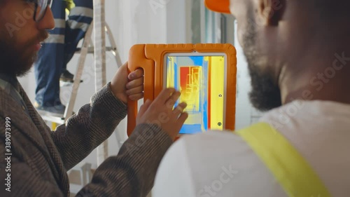 Back view of professional construction team using infrared camera on tablet checking heating system photo