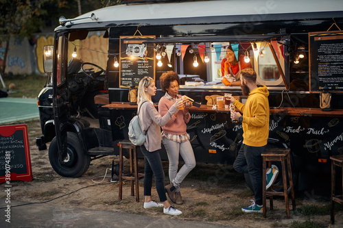 group of people socializing while eating outdoor in front of modified truck for fast food