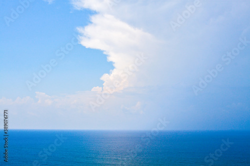 An aerial view of eternal blue sea or ocean with sunny and cloudy sky.