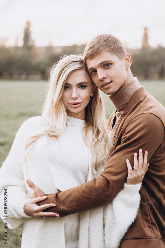 Fototapeta premium Beautiful young couple in autumn walks with dogs, pomeranian, in the park