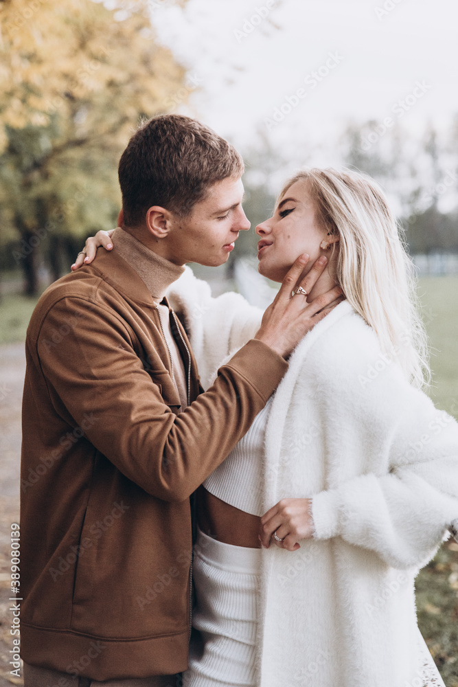 Beautiful young couple in autumn walks with dogs, pomeranian, in the park Beautiful young couple in autumn walks with dogs, pomeranian, in the park