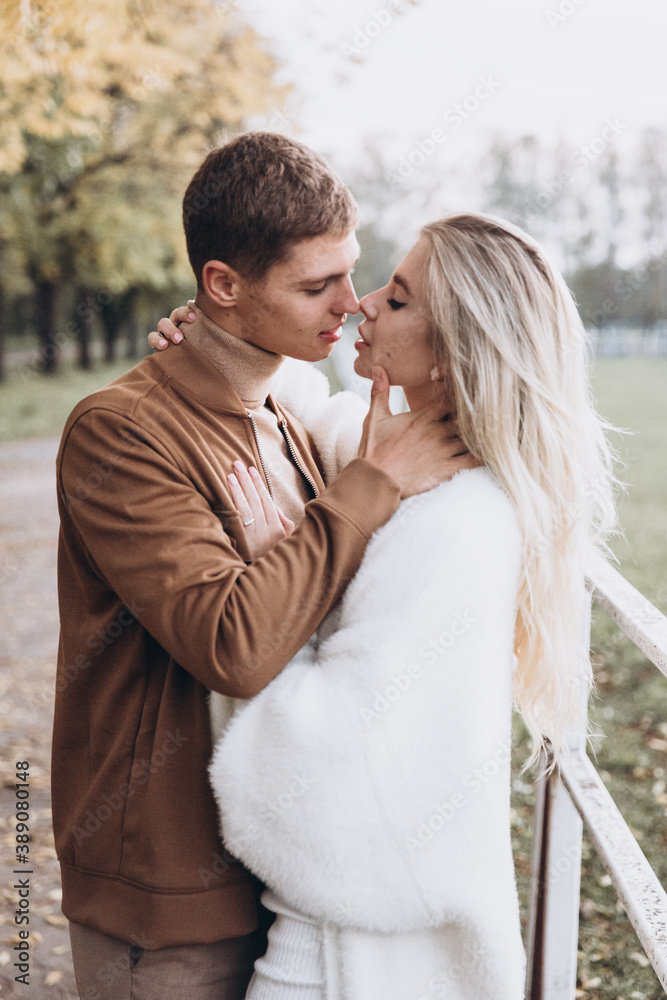 Fototapeta premium Beautiful young couple in autumn walks with dogs, pomeranian, in the park