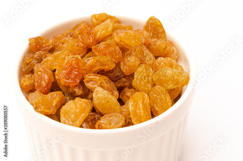 Appetizing yellow raisins in a light plate on a white background