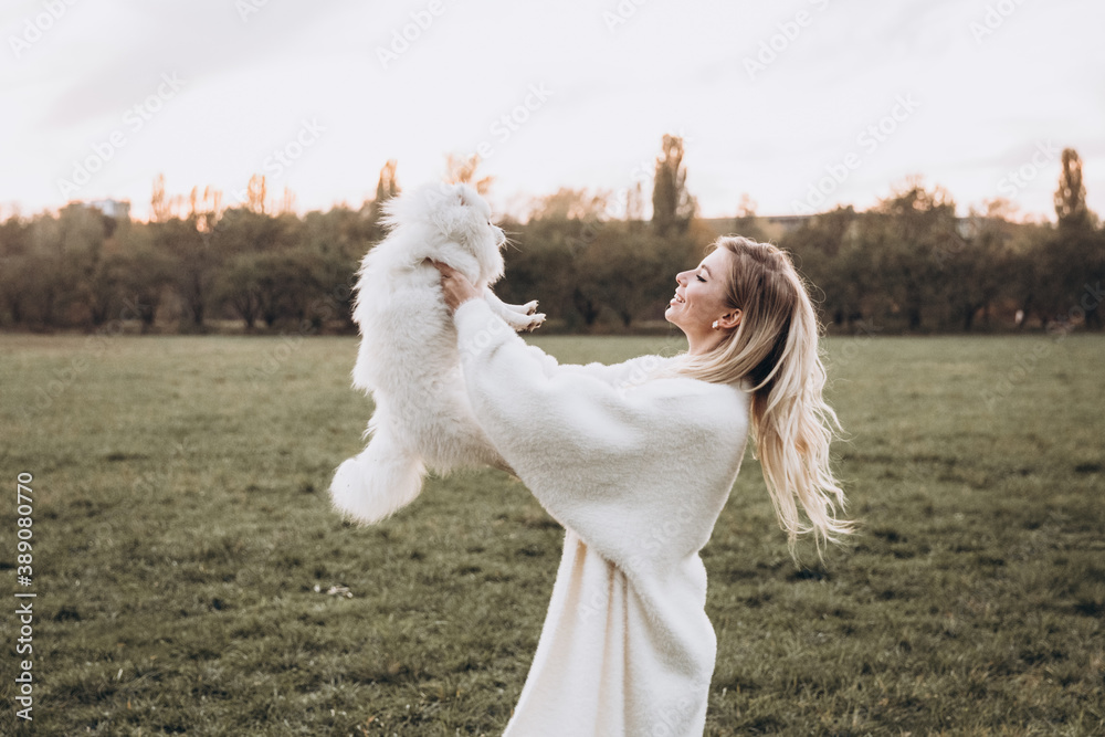 Beautiful young couple in autumn walks with dogs, pomeranian, in the park Beautiful young couple in autumn walks with dogs, pomeranian, in the park