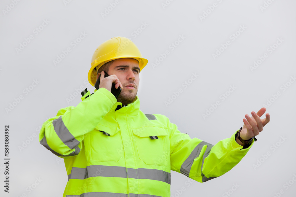 Young engineer or worker with green protective work wear talking on mobile phone