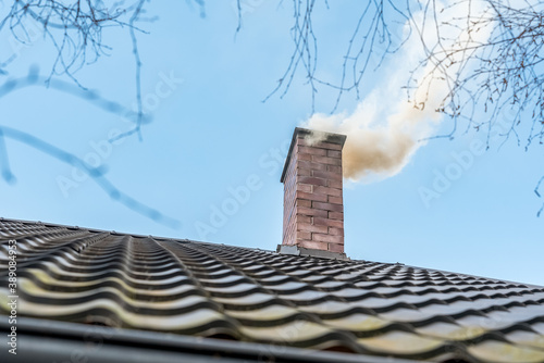 Chimney on the roof of a detached house. The smoke.