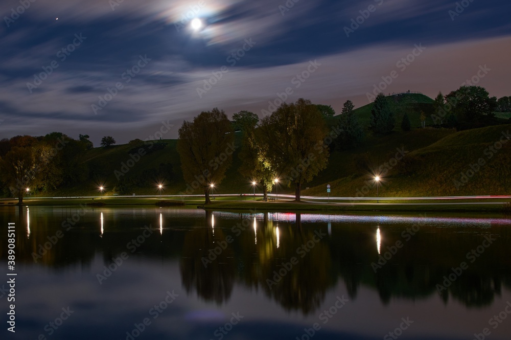 Long exposure of city lights and clouds in a park at night. Long exposure of light reflections in a lake in Munich at night.