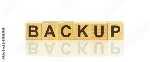 Wooden Blocks with the text: backup. The text is written in black letters and is reflected in the mirror surface of the table.