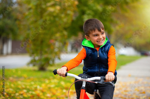 Happy child. Boy on a bike in a city park. The concept of relaxation and fun time. Photo with empty space