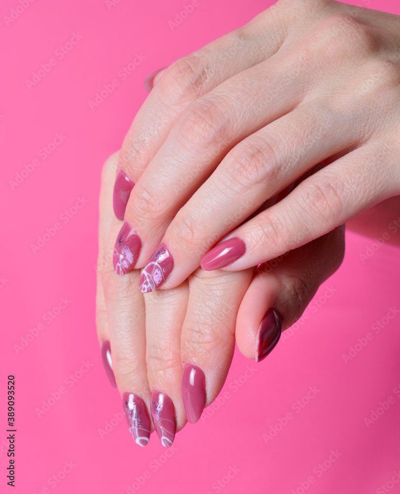 female hands with painted nails on pink background.