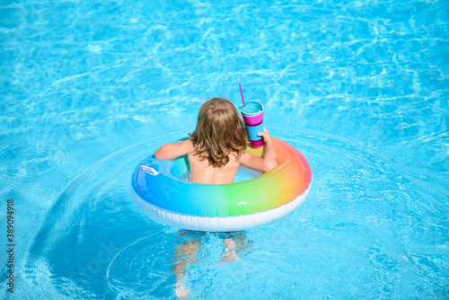 Kid with colorful swim ring in swimming pool on summer day. Water toys and floats for child. Healthy sport for children. Family beach vacation.