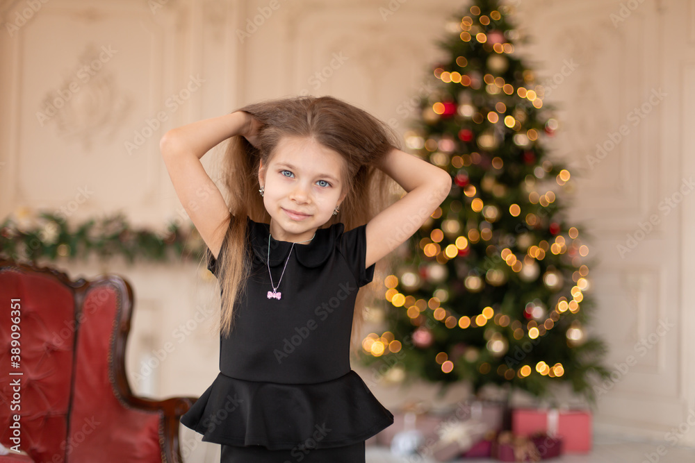 A little girl opens a Christmas present from Santa. Christmas tale. Happy childhood A little girl opens a Christmas present from Santa. Christmas tale. Happy childhood