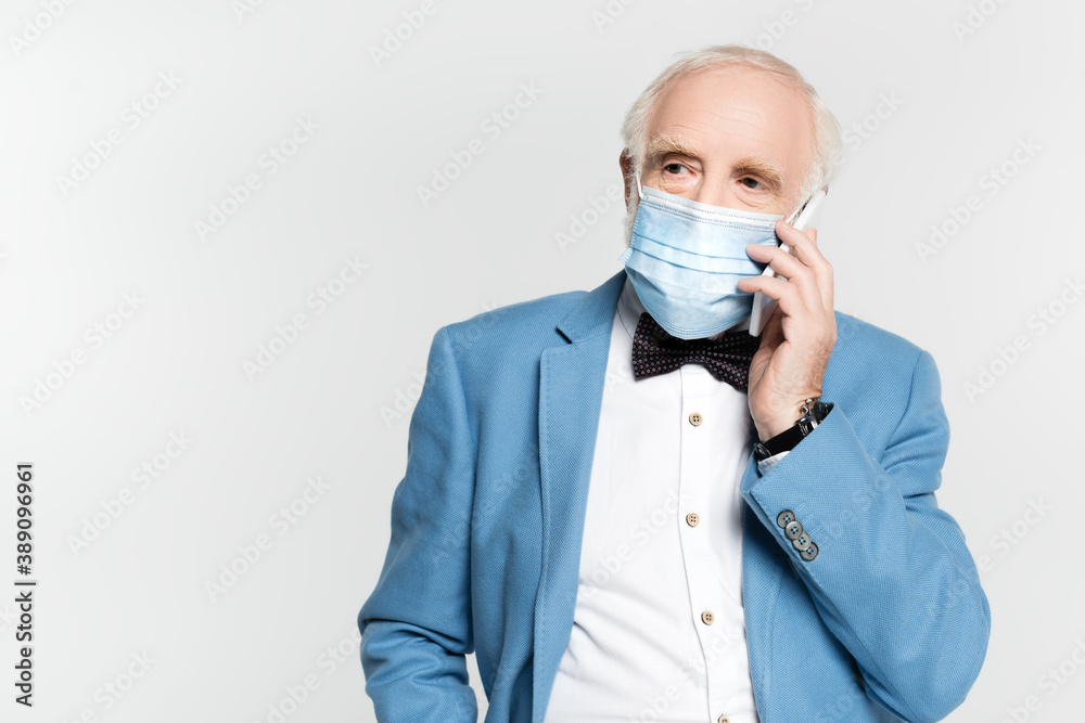 Senior man in medical mask talking on smartphone isolated on grey Senior man in medical mask talking on smartphone isolated on grey