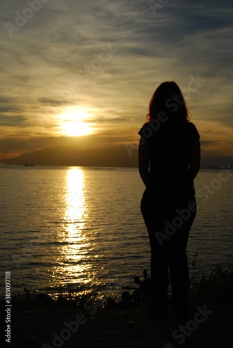 silhouette of a woman on the beach with the sunset in background © victor
