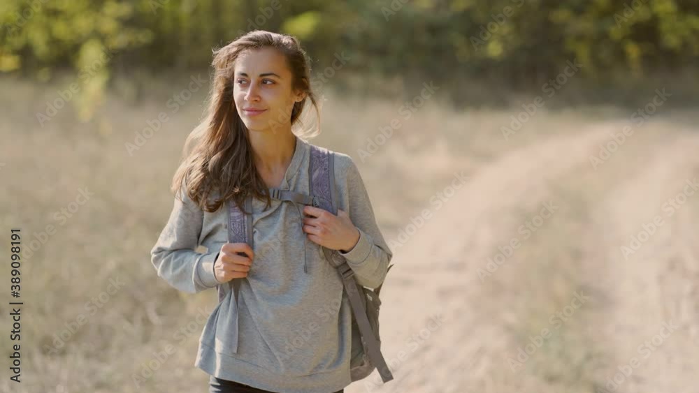 beautiful Carefree hiker young woman walking by rural road along forest, enjoying fall autumn season. Concept people and nature, outdoors portrait beautiful Carefree hiker young woman walking by rural road along forest, enjoying fall autumn season. Concept people and nature, outdoors portrait