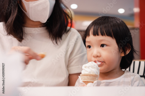 Asian 3 year old girl with  face eat ice cream cone. Concept for  sweet food and family life.