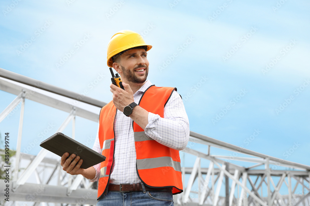 Professional engineer with tablet and walkie talkie near high voltage