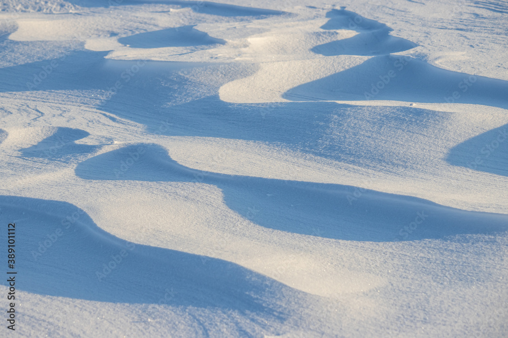 Snow texture. Wind sculpted patterns on snow surface. Wind in the tundra and in the mountains on the surface of the snow sculpts patterns and ridges (sastrugi). Arctic, Polar region. Winter background Snow texture. Wind sculpted patterns on snow surface. Wind in the tundra and in the mountains on the surface of the snow sculpts patterns and ridges (sastrugi). Arctic, Polar region. Winter background