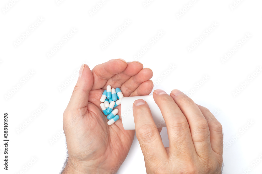 A man pours the pills out of the bottle. hands with pills on, spilling pills out of bottle on white background A man pours the pills out of the bottle. hands with pills on, spilling pills out of bottle on white background