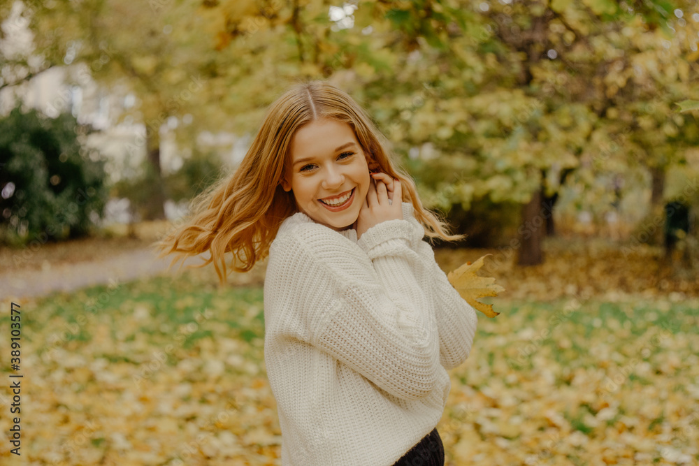 A teenager runs in the park and laughs, autumn has come. Autumn leaves and trees on a green background. The girl is joyful, smiling and sweet A teenager runs in the park and laughs, autumn has come. Autumn leaves and trees on a green background. The girl is joyful, smiling and sweet