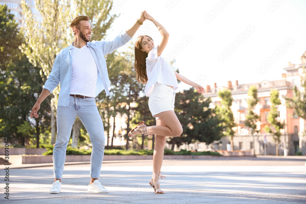 Lovely young couple dancing together outdoors on sunny day