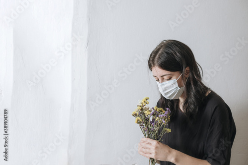 masked girl tries to sniff flowers but cannot enjoy life due to mask quarantine and virus