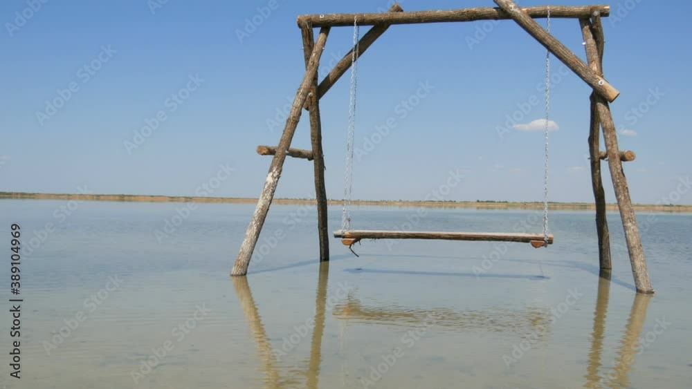 A lonely Wooden swing on the water is picturesquely located on a salt lake, recreation relax concept. A lonely Wooden swing on the water is picturesquely located on a salt lake, recreation relax concept.
