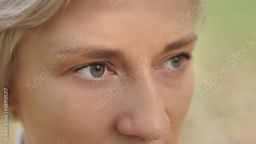 Close up. Green eyes of young caucasian blond woman in the park. High quality photo