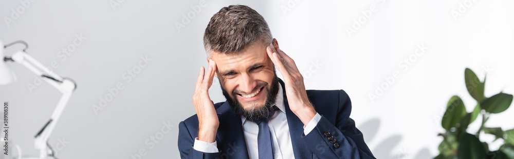 Businessman in formal wear suffering from headache in office, banner Businessman in formal wear suffering from headache in office, banner