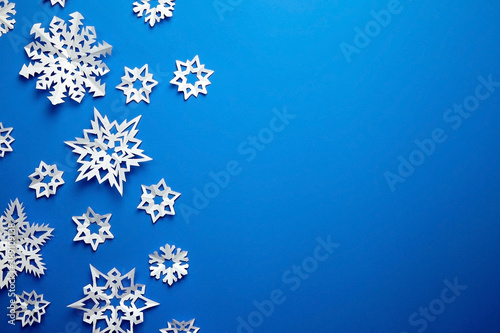 Composition with white paper snowflakes on blue background