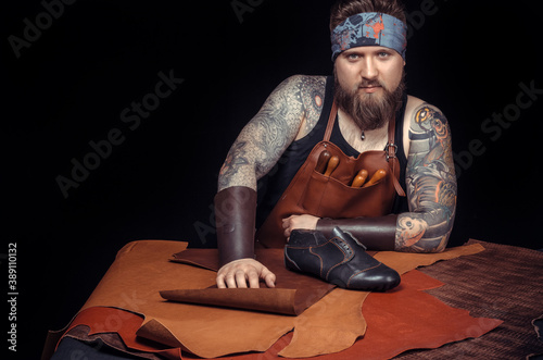 Professional Tanner working with leatherwork at the workplace photo