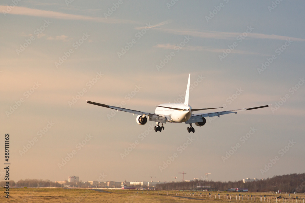 Airplane landing at airport in sunny day, back view. Silhouette of passenger aircraft almost landed at the runway. Vacation, aviation Airplane landing at airport in sunny day, back view. Silhouette of passenger aircraft almost landed at the runway. Vacation, aviation
