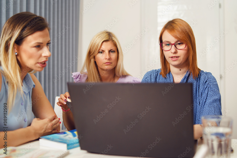 Group of women female only colleagues working together on project sitting by the desk using laptop at work in the office - Millennial boss and entrepreneurs having meeting brainstorming concept Group of women female only colleagues working together on project sitting by the desk using laptop at work in the office - Millennial boss and entrepreneurs having meeting brainstorming concept
