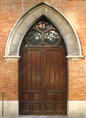 decorated door of wood and glass, with pointed arch on a facade of a gothic building- elvish style of architecture photo