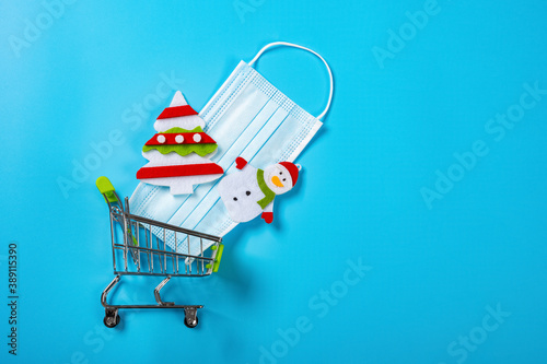 shopping cart with medical mask and Christmas decorations on blue background photo