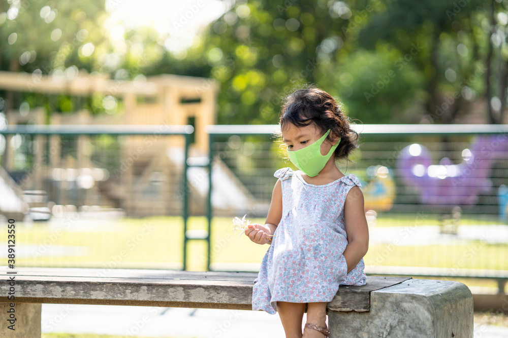 girl sitting on park bench wearing healthy face mask to prevent virus, pm25 and germs