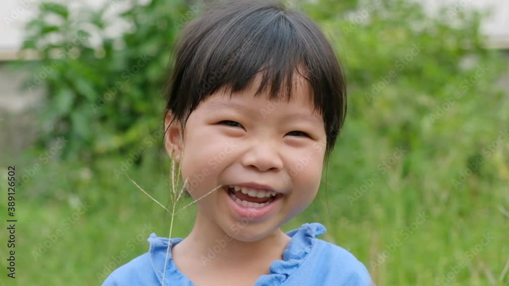 Portrait of little girl looking at camera, smiles and laughs at the park Portrait of little girl looking at camera, smiles and laughs at the park