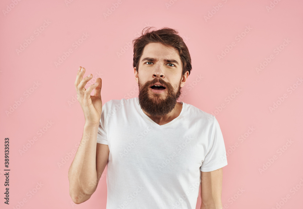 Portrait of a young man with a beard in a white T-shirt on a pink background Portrait of a young man with a beard in a white T-shirt on a pink background