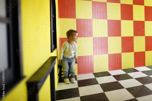 A child in a mask plays in a children's science amusement park, a child plays with illusions in a children's center, quarantine and mask mode in public places